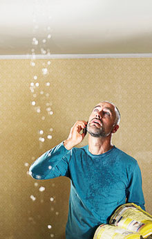 Man on the phone with a plumber with water leaking from his sealing